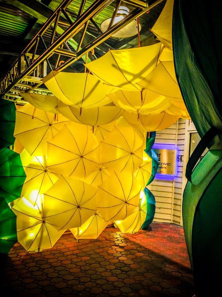A bunch of yellow umbrellas are hanging from the ceiling