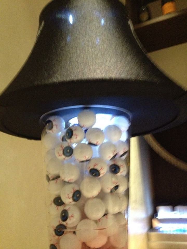 A jar filled with fake eyes and a hat on top of it.