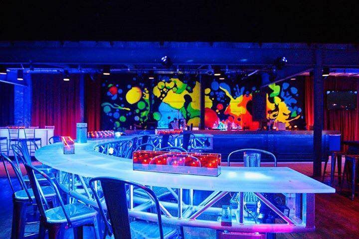 A bar with a long table and chairs in a dark room.
