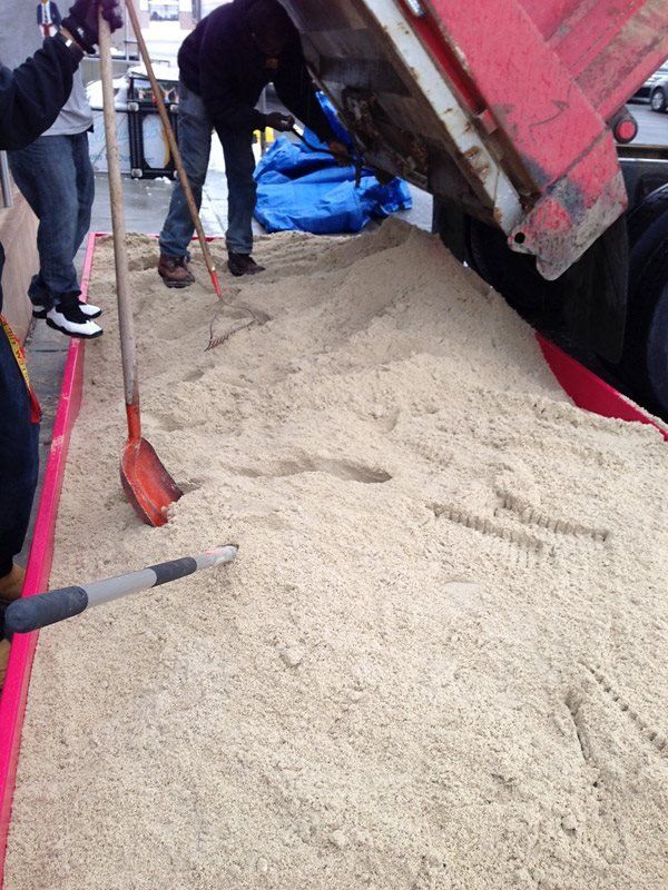 A pile of sand is being loaded into a truck