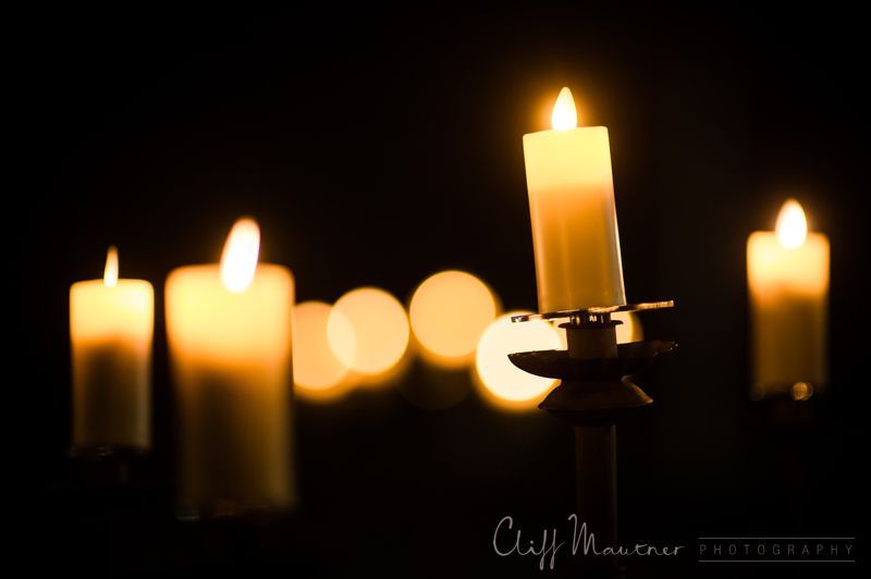 A group of lit candles in a dark room by cliff manner photography
