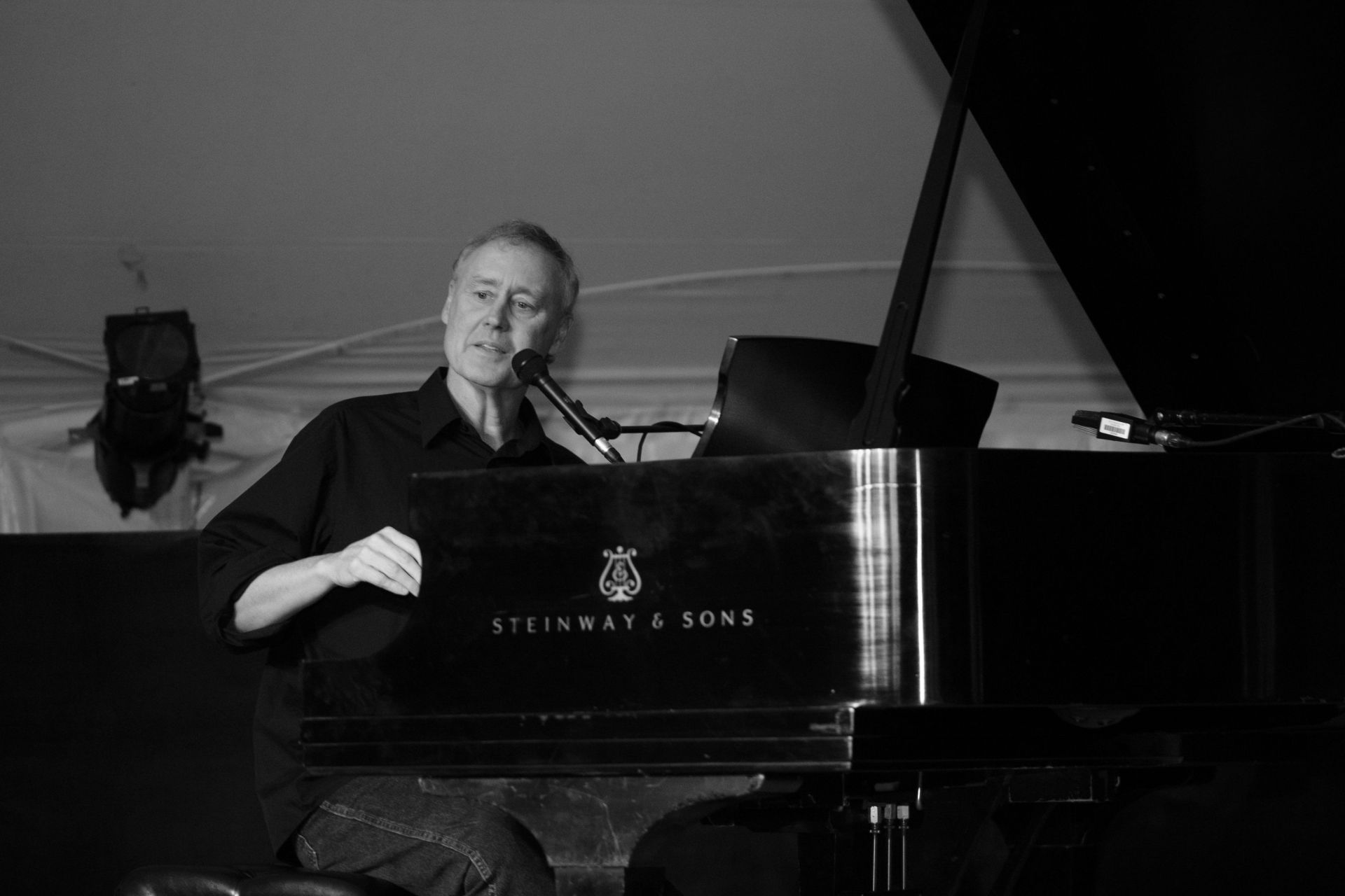 A man is playing a piano and singing into a microphone