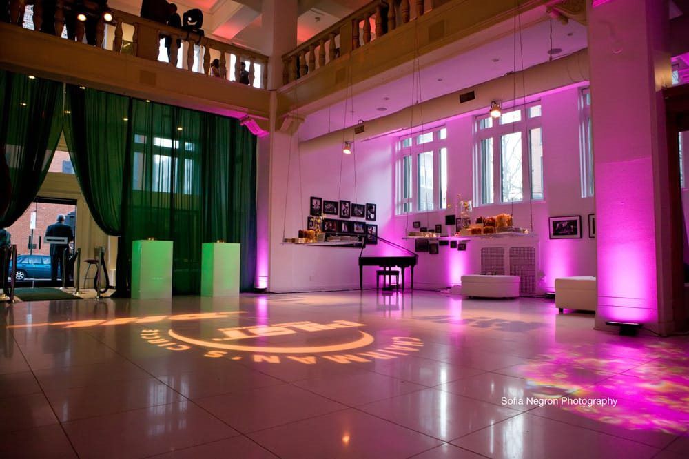 A large room with a dance floor and a green curtain.