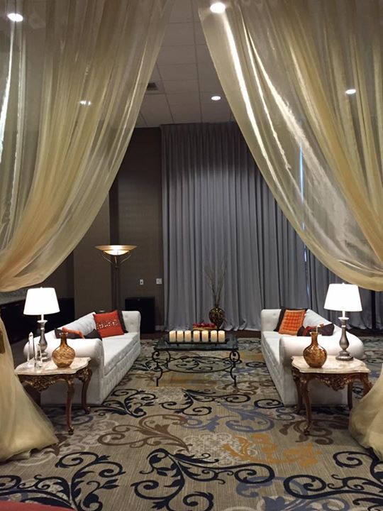 A living room with a couch , table , lamps and curtains.