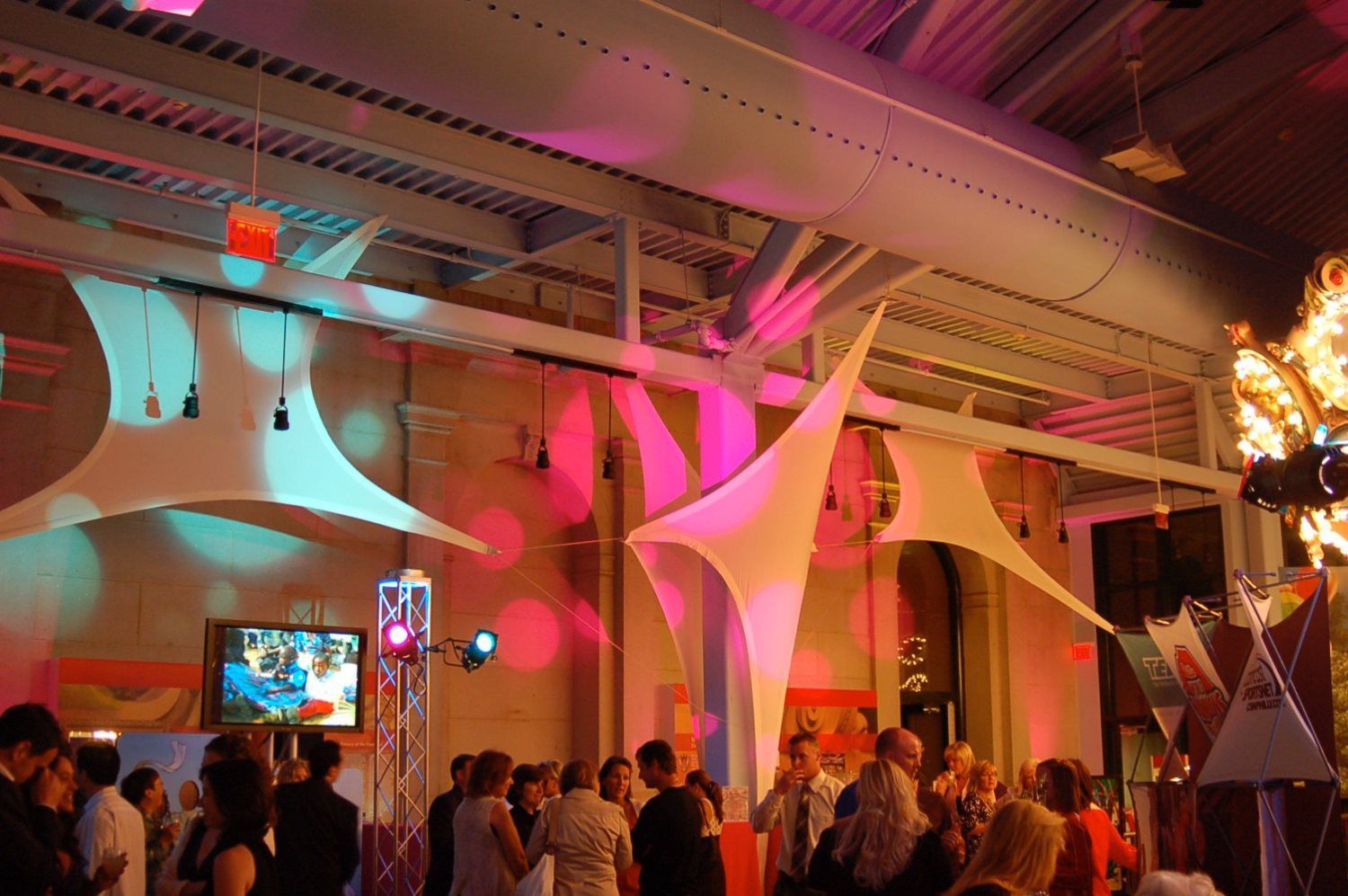 A group of people are dancing in a room with a tv on the wall.