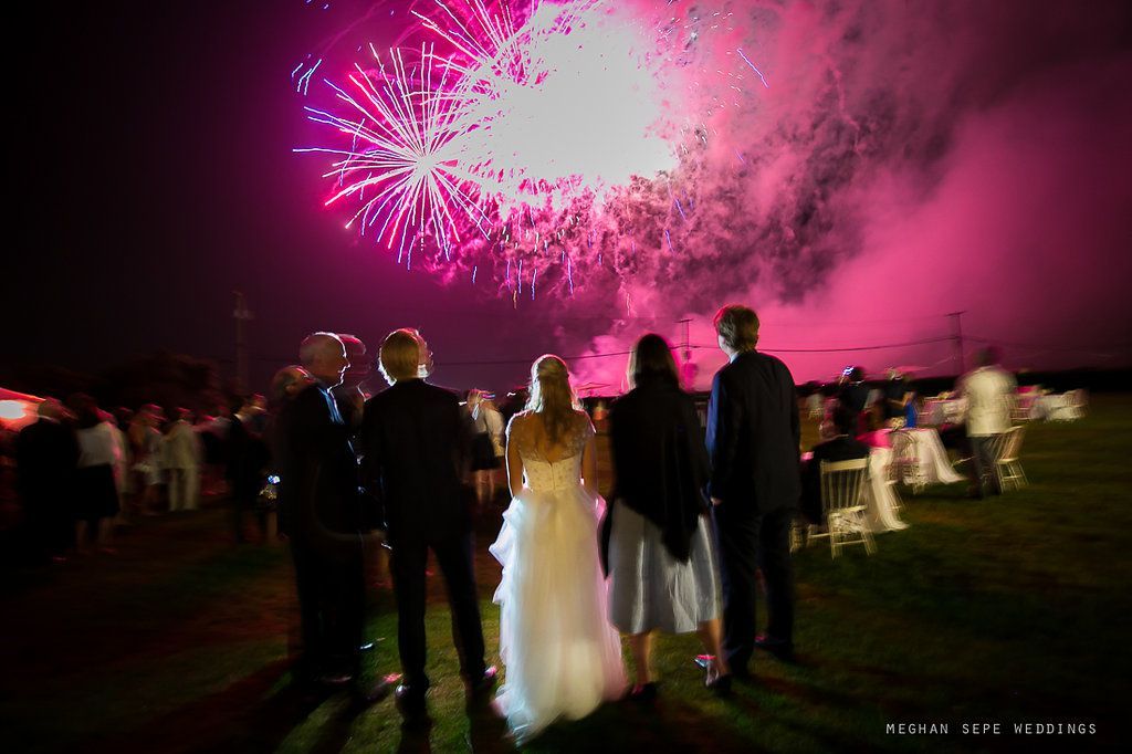 A bride and groom are standing in front of a fireworks display.