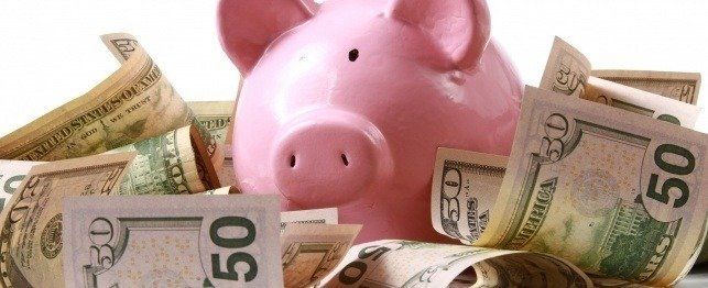 Pink piggy bank surrounded by cash.
