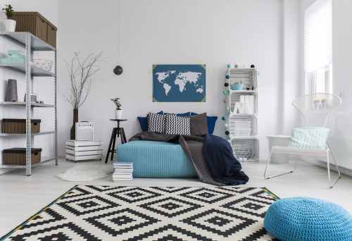 una stanza con un letto, uno scaffale in ferro e un tappeto bianco e nero