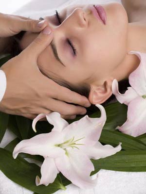 A woman is getting an indian head massage with flowers and leaves.