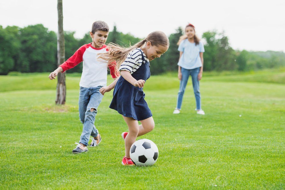 Ein Junge und ein Mädchen spielen Fußball auf einem üppigen grünen Feld.