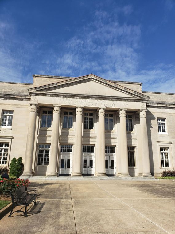Gray stone building with columns under a blue sky, an outdoor setting.