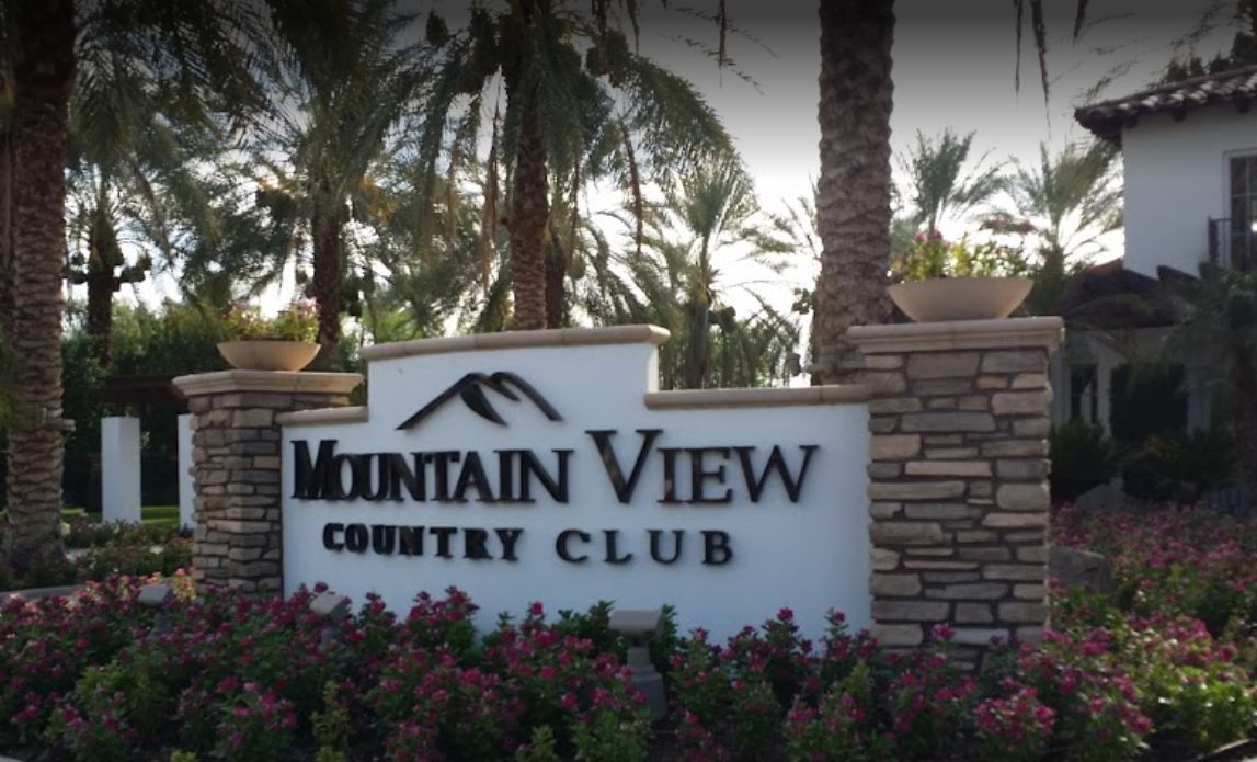 Mountain View Country Club sign with landscaping, palm trees, and building.