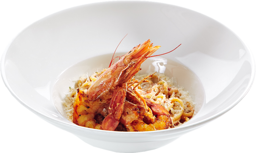Pasta con gamberi servita in una ciotola bianca, condita con salsa all'arancia ed erbe aromatiche.