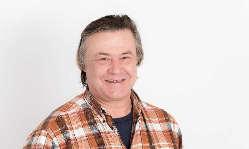 A man in a plaid shirt is smiling for the camera.