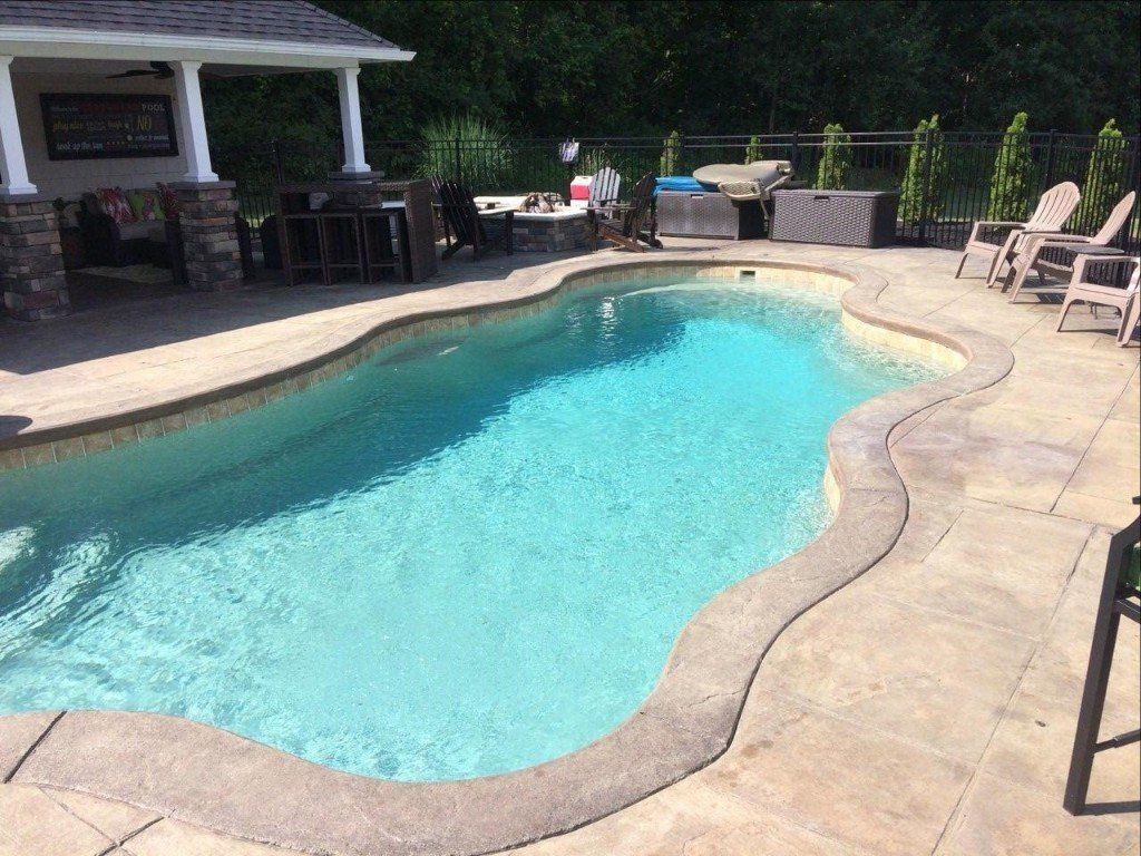 Backyard swimming pool with turquoise water, patio seating, and a shaded outdoor bar area