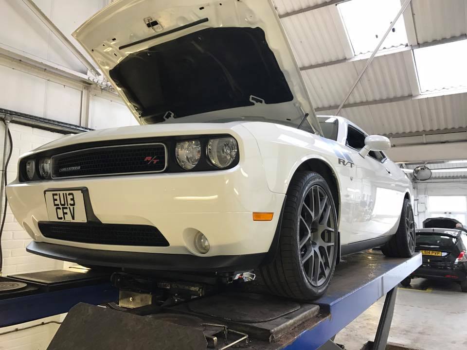 White car with hood raised in garage
