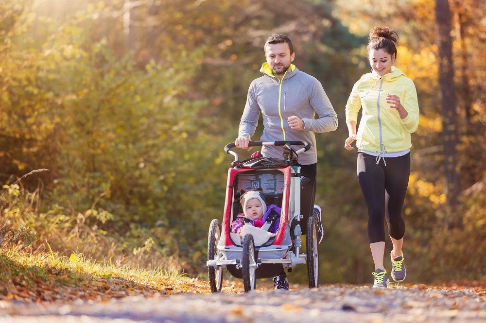 coppia che fa jogging con bebè nella carrozzina