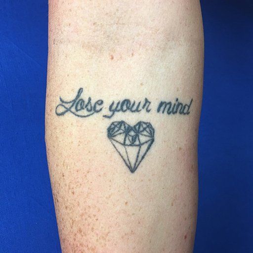 A tattoo on a person 's arm that says lose your mind