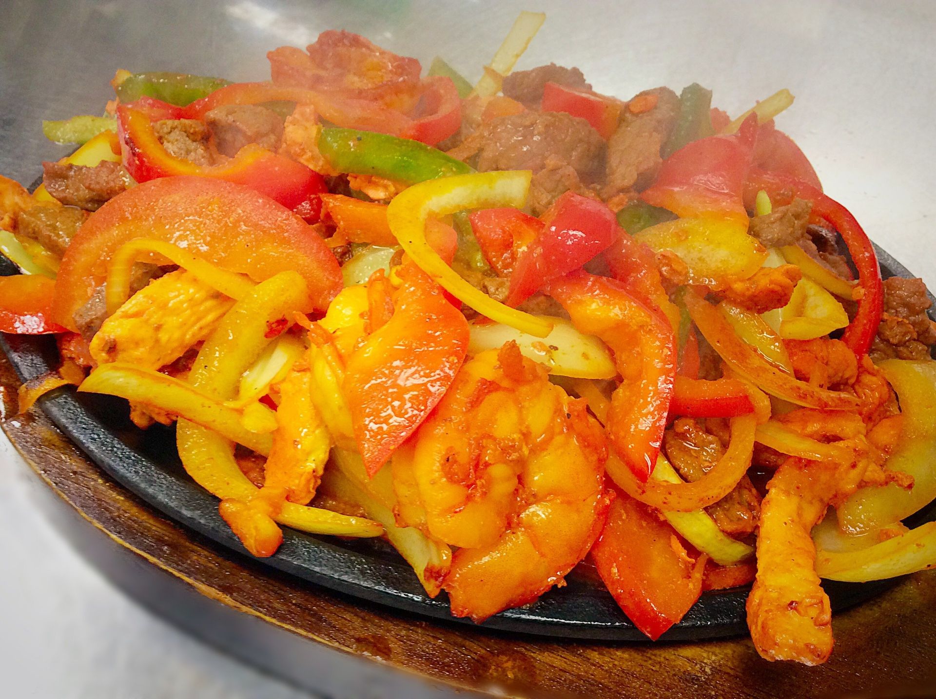 Sizzling fajitas: steak, peppers, and onions on a hot cast iron plate, vibrant colors and steam.