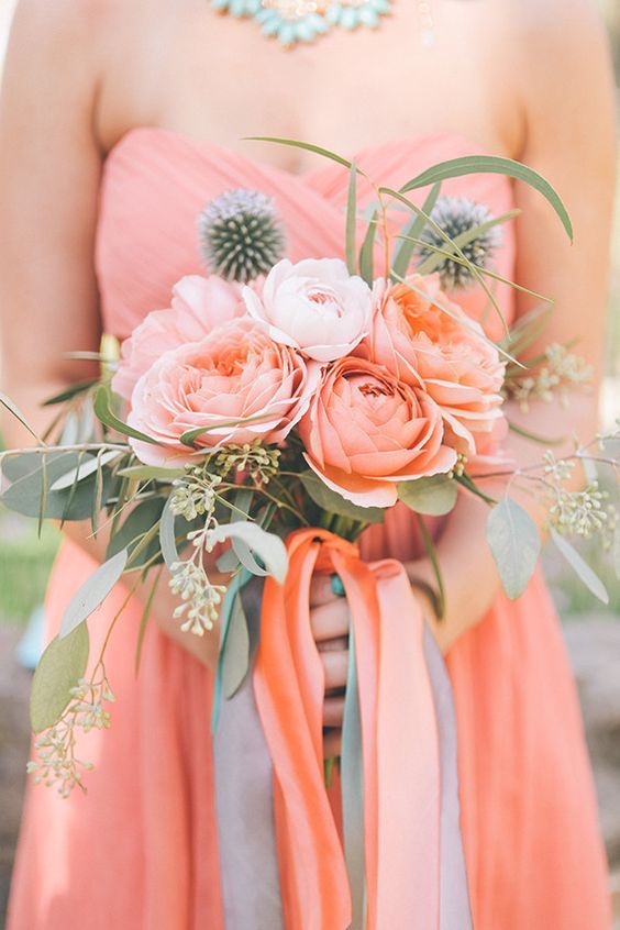A woman in a pink dress is holding a bouquet of flowers.