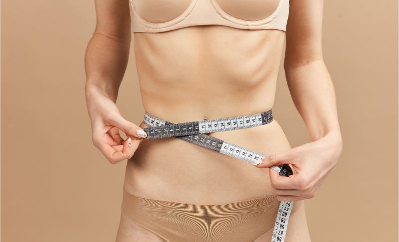 ragazza con disordine alimentare che misura il girovita
