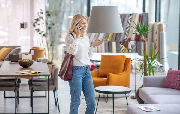 In store dining furniture — Springfield, OR — Northwest Home Furnishings A person talking on a mobile phone while standing in a furniture store, surrounded by chairs, tables, and decor.