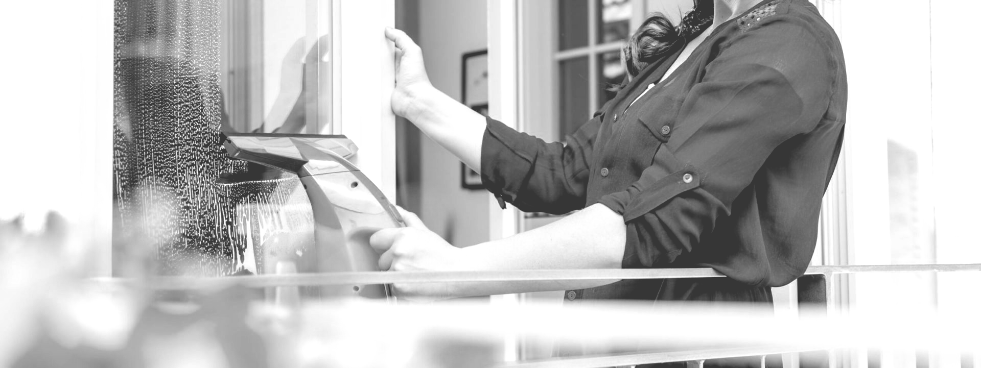 A black and white photo of a woman cleaning a window.
