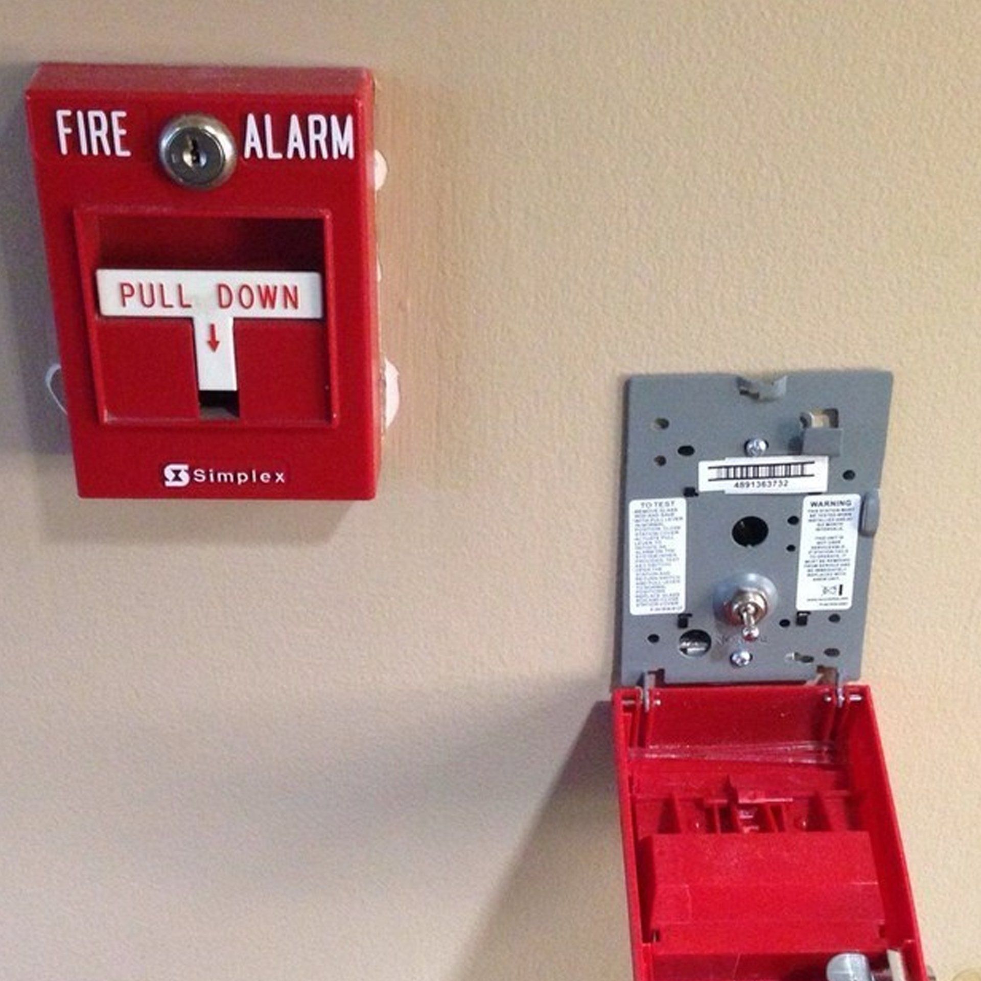 A red fire alarm pull down box on a wall