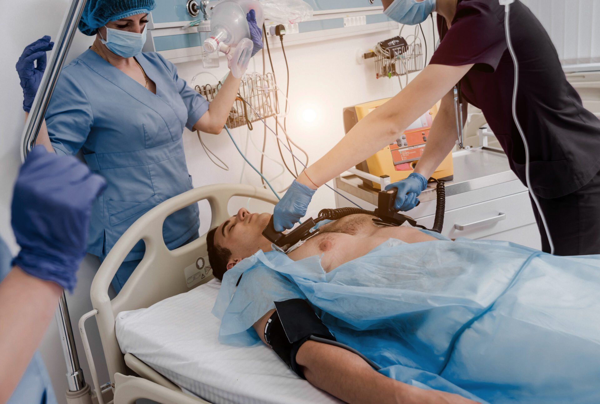 A man is laying in a hospital bed being examined by two nurses.