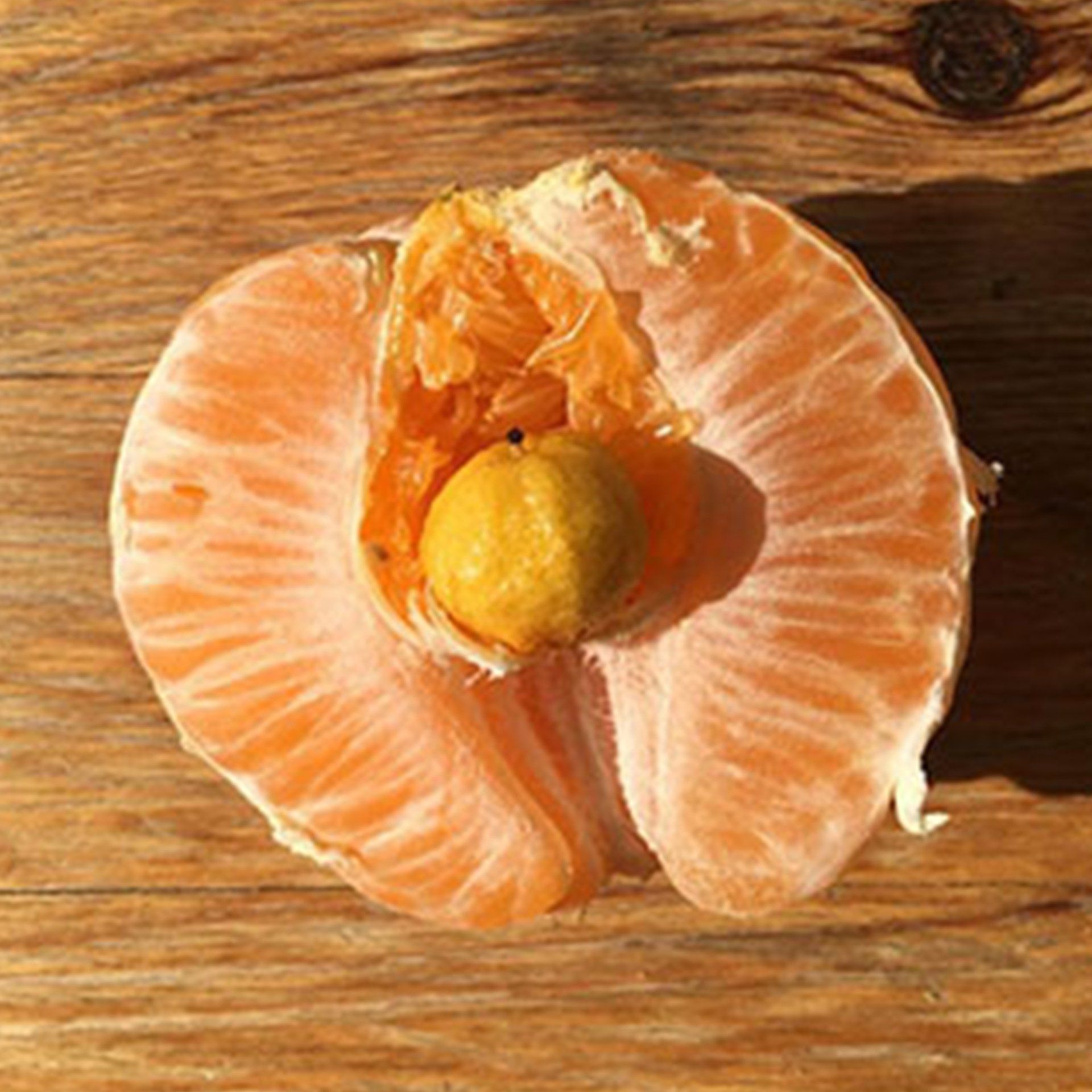 A peeled orange with a smaller orange inside inside of it