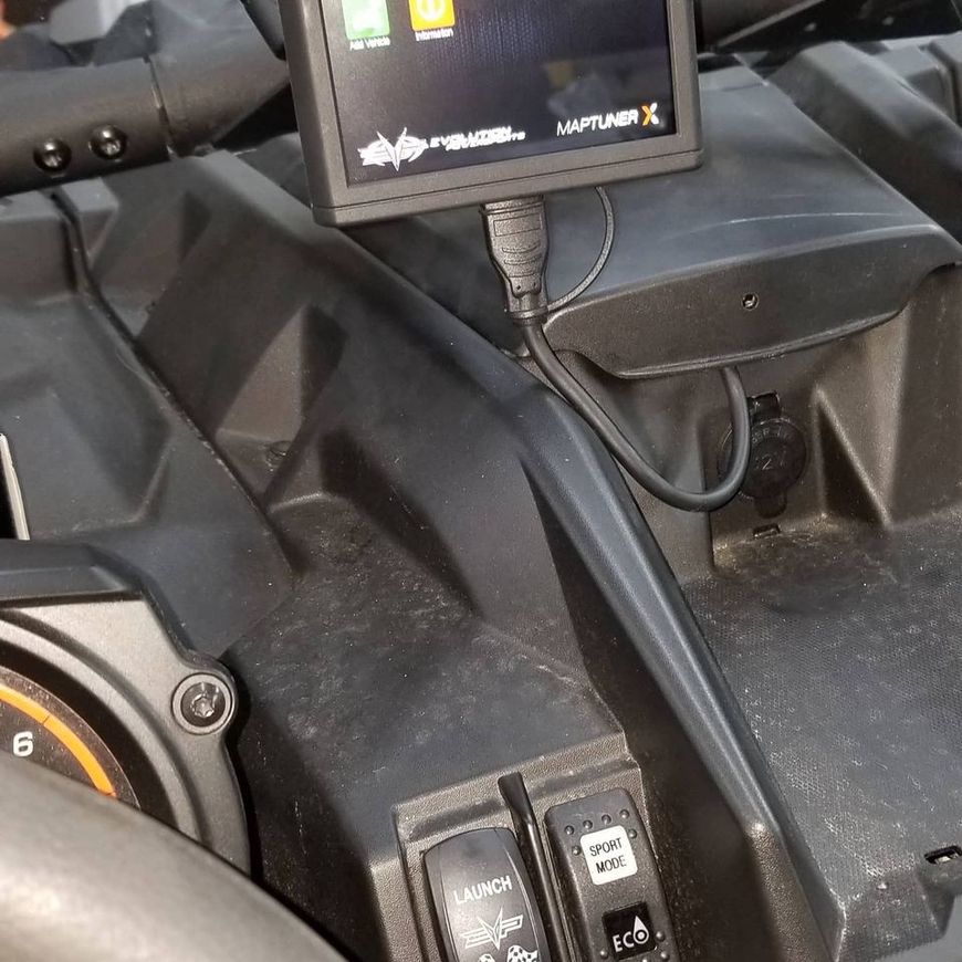 A digital PV3 tuner screen mounted on the black dashboard of an off-road vehicle near accessory switches.