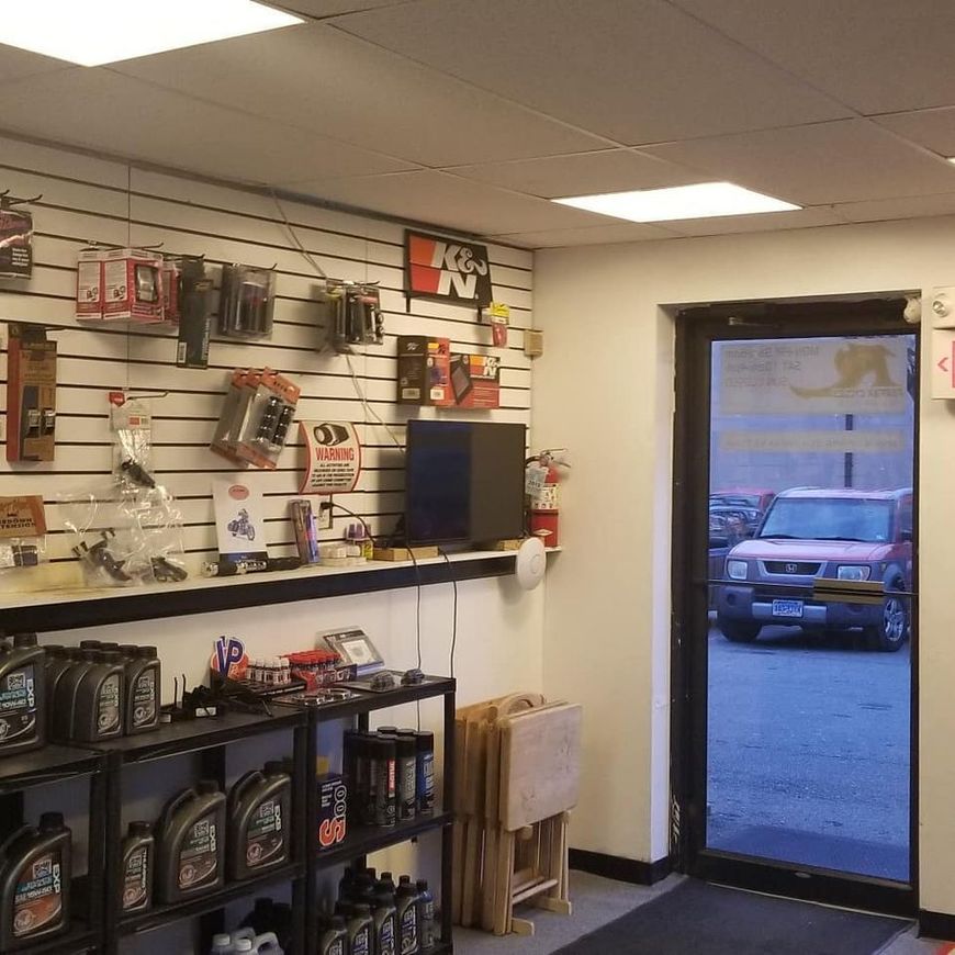 A retail shop interior with automotive products on a wall display and shelves, with a view of a parked car through a door.