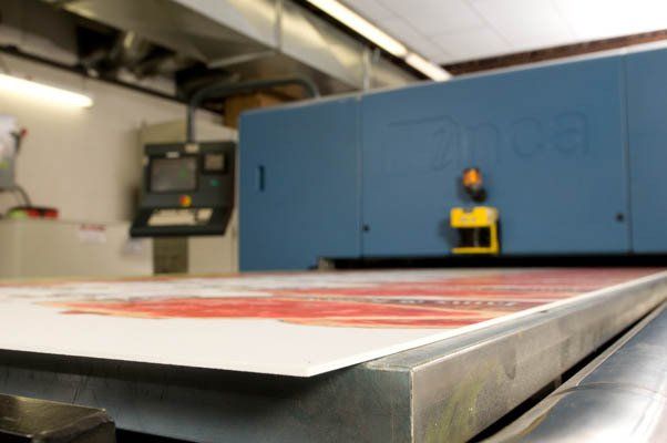 A large piece of paper is being printed on a machine in a factory