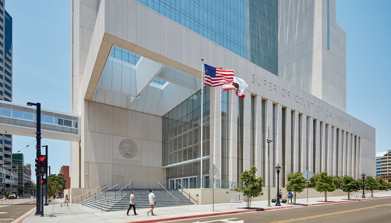 Exterior view of the San Diego Central Courthouse building on a sunny day. Pedestrians walk near the entrance.