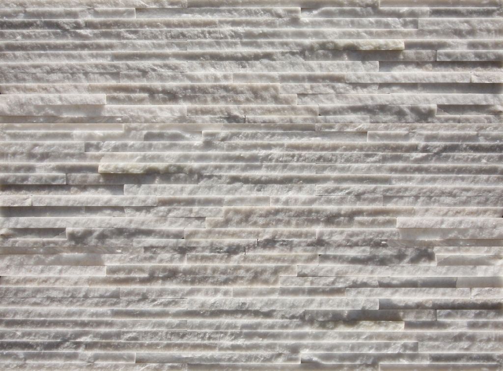 Weiße Steinmauer mit horizontalen, strukturierten Linien.