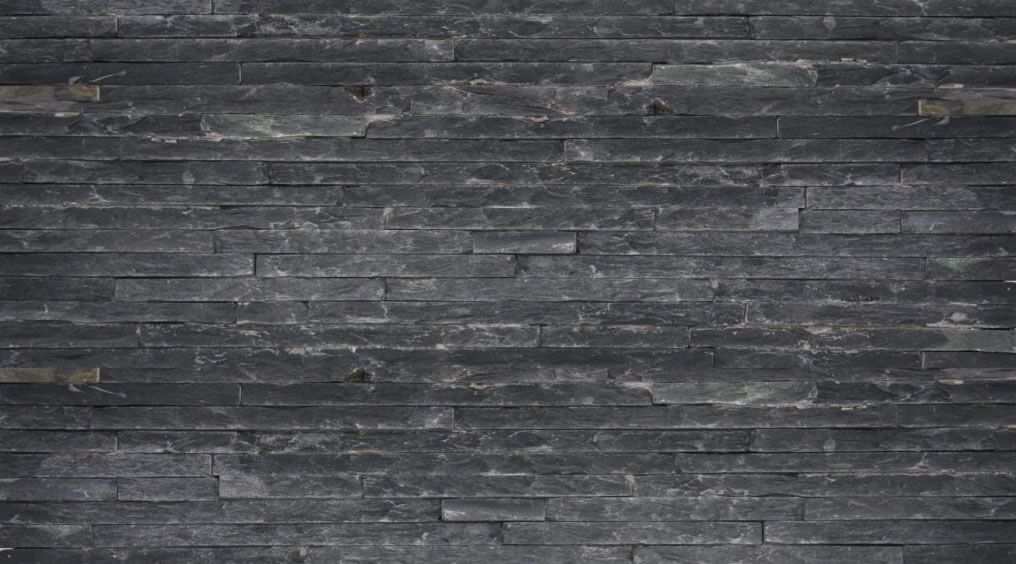 Dunkelgraue Steinmauer mit horizontalen, rechteckigen Blöcken.