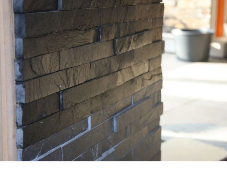 Schwarze Schieferfliesenwand mit sichtbarer Struktur und unregelmäßigen Kanten.