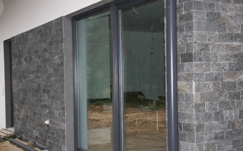 Dunkelgraue Backsteinwand mit einer Glasschiebetür.