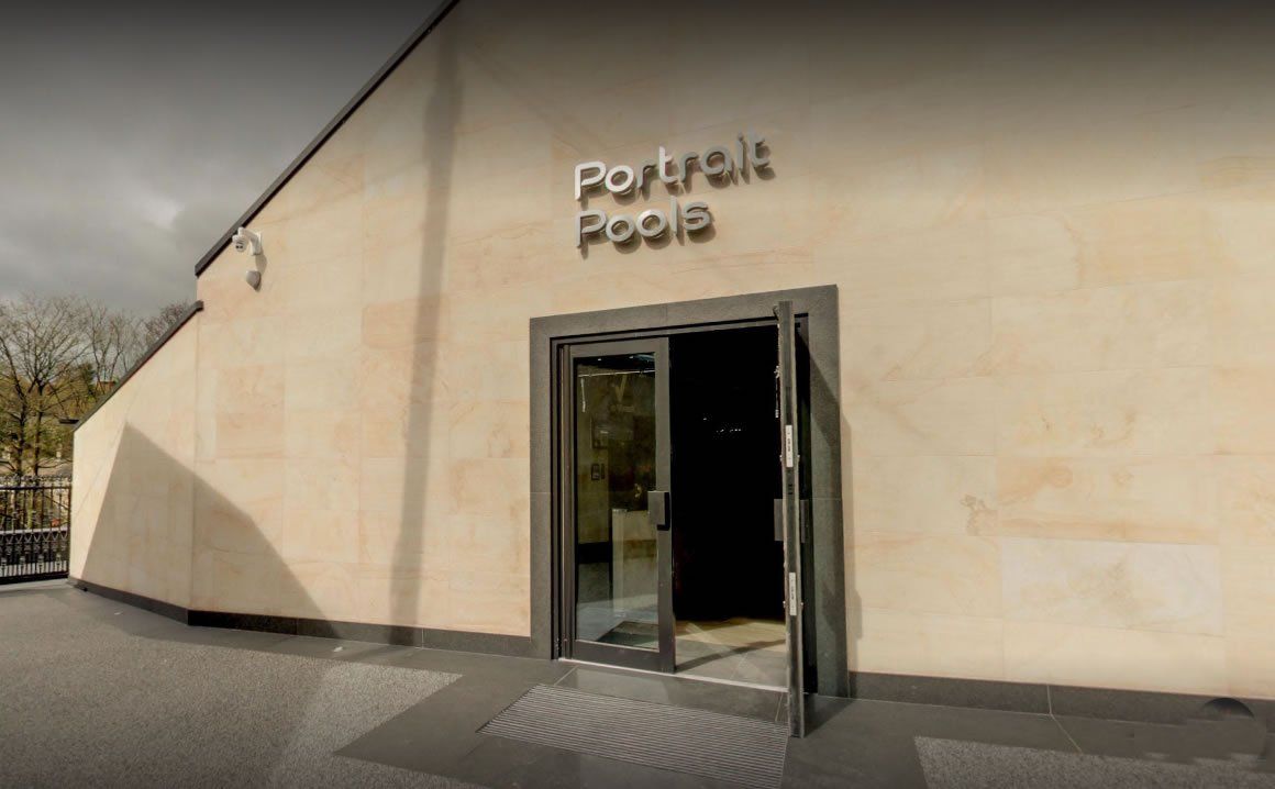 Eingang zur Galerie „Portrait Poole“ mit offener Glastür und Beschilderung an einem hellen Steingebäude.