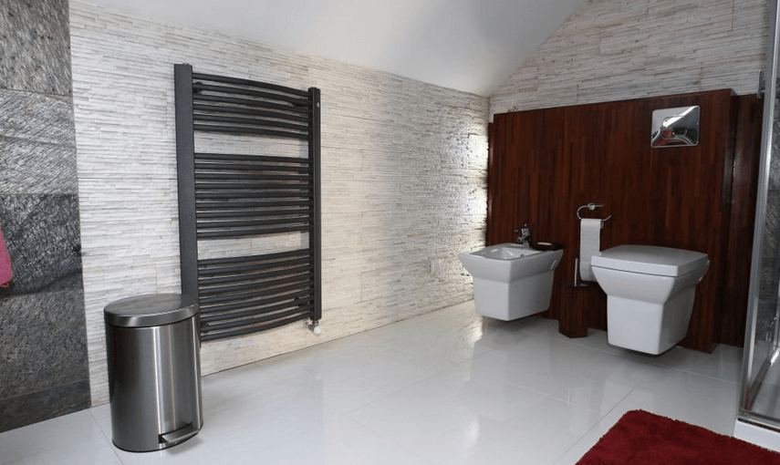 Modernes Badezimmer mit weißen Wänden, beheiztem Handtuchhalter, Toilette und Bidet.