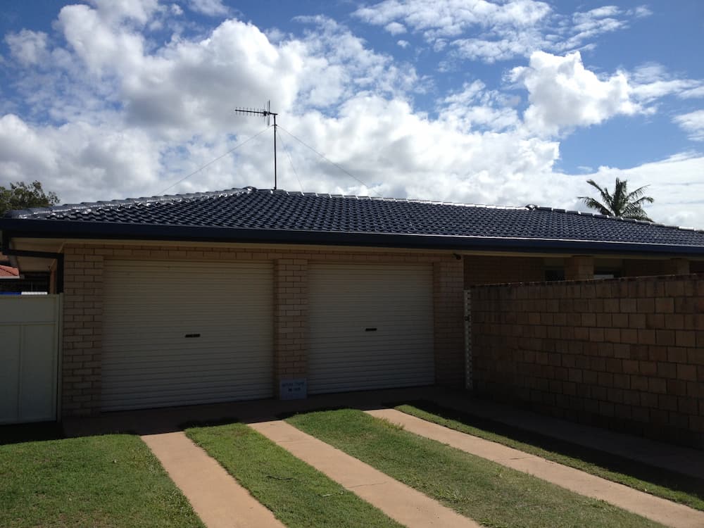 A House With a Blue Roof and White Garage Doors — Killiby & Co Roofing Pty Ltd in Tweed, NSW