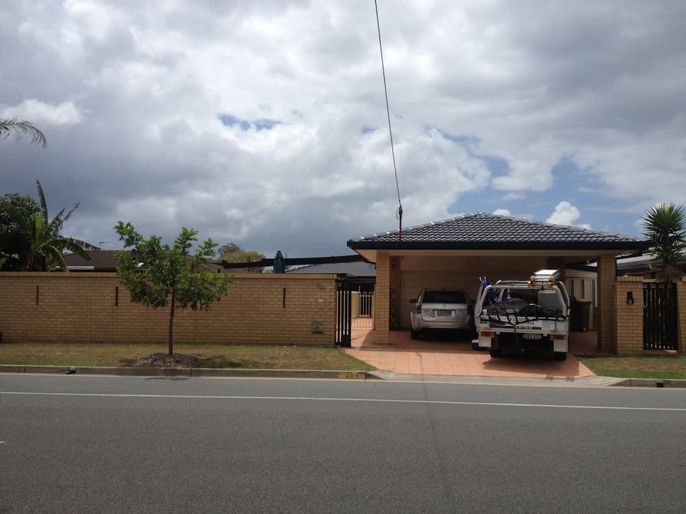 Two Cars Are Parked in Front of a House on a Cloudy Day — Killiby & Co Roofing Pty Ltd in Tweed, NSW