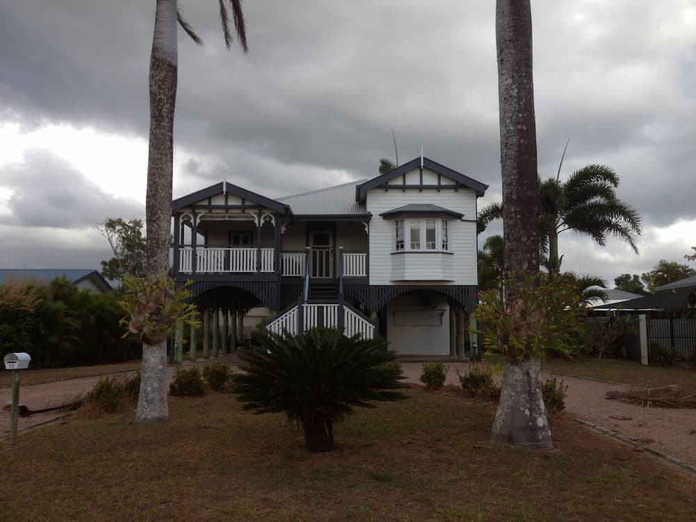 A House With Palm Trees in Front of It on a Cloudy Day — Killiby & Co Roofing Pty Ltd in Tweed, NSW