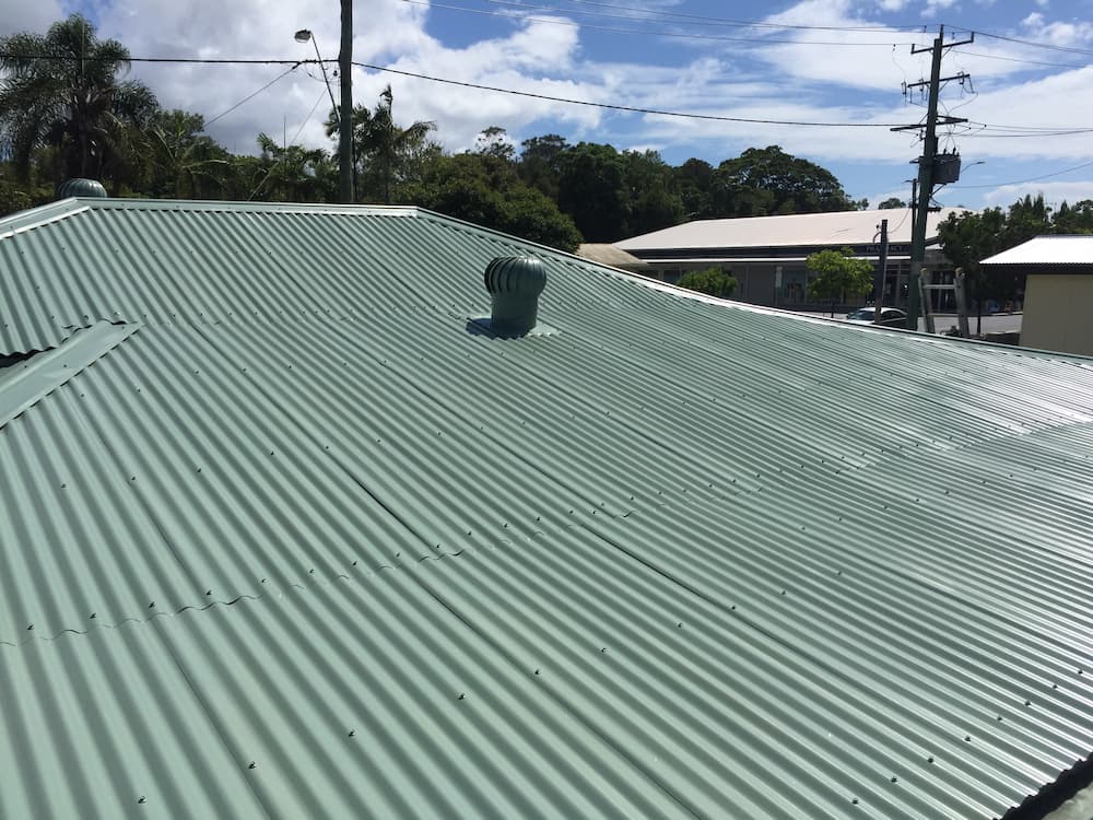 A Green Corrugated Metal Roof With a Vent on Top of It — Killiby & Co Roofing Pty Ltd in Tweed, NSW