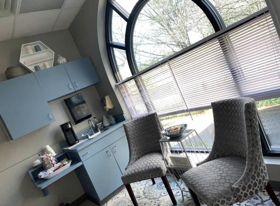 Waiting area with two chairs, arched window, blue cabinets, and a small table.