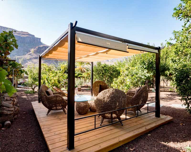 Eine Holzterrasse mit Stühlen und einem Tisch unter einer Pergola.