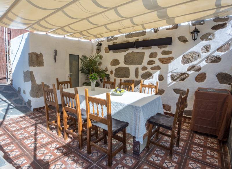 Eine Terrasse mit Tisch und Stühlen unter einem Baldachin.