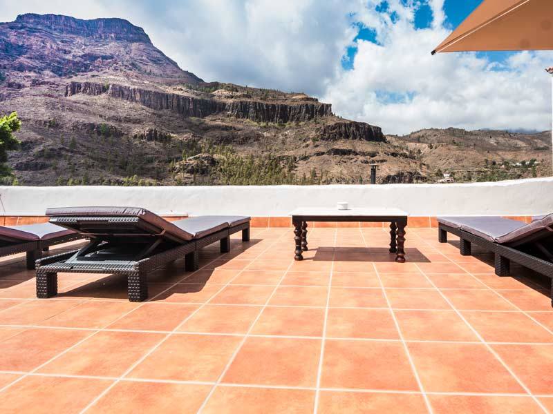 Eine Terrasse mit Stühlen und einem Tisch mit Bergen im Hintergrund