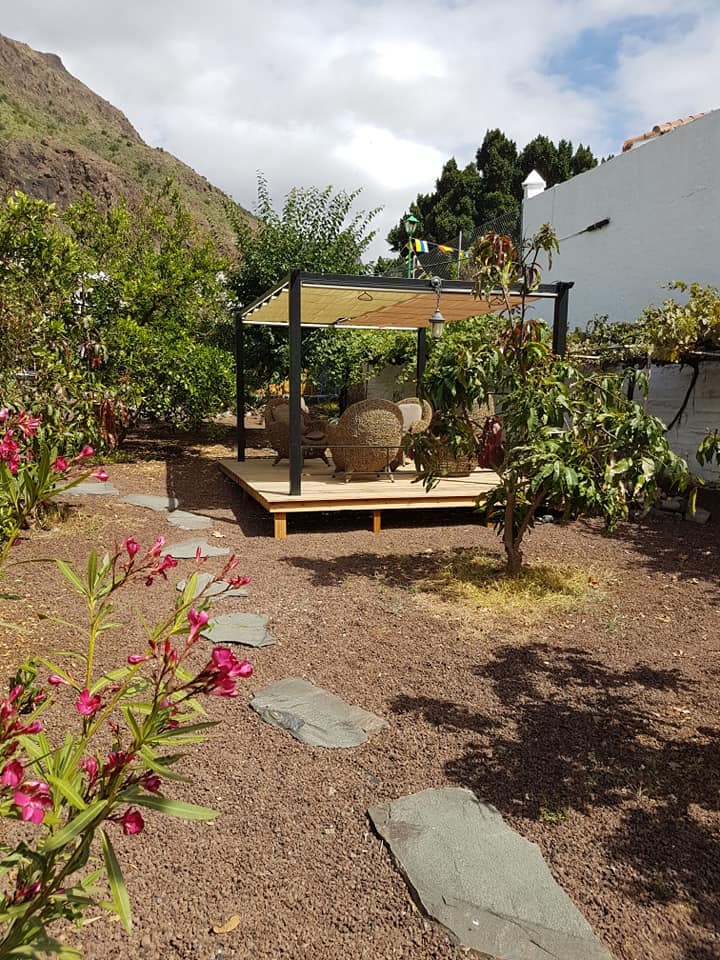 Ein Garten mit Pergola, Stühlen und Blumen.