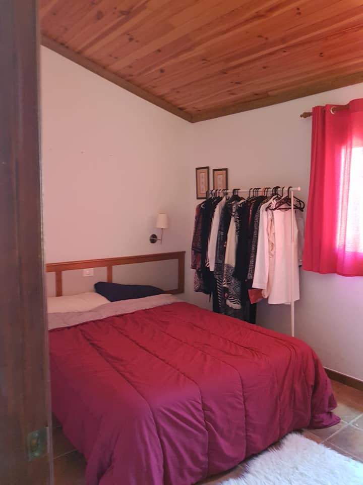 Ein Schlafzimmer mit einem Bett und an einem Ständer hängender Kleidung